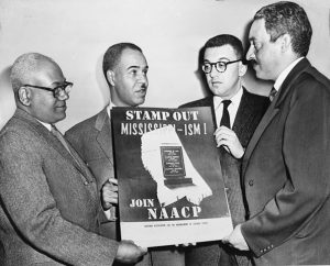 Holding a poster against racial bias in Mississippi in 1956, are four of the most active leaders in the NAACP movement: Henry Moon, Roy Wilkins, Herbert Hill, and Thurgood Marshall