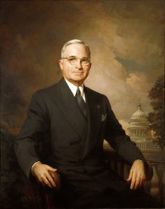 Painting of Truman with the U. S. Capitol visible in the background. He is seated.