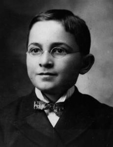 Harry Truman at age 13 wearing a suit, wire-rim glasses, and a neat bow tie.