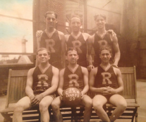 Basketball Champion Team. Six young men wearing jerseys marked "R." The man in center front holds a basketball saying "C O A N Champs 30"